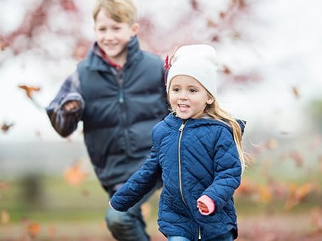 2 Kinder spielen draußen im Herbst