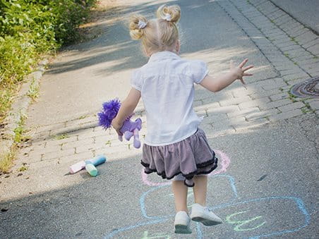 Kind spielt Hüpfspiel im Freien