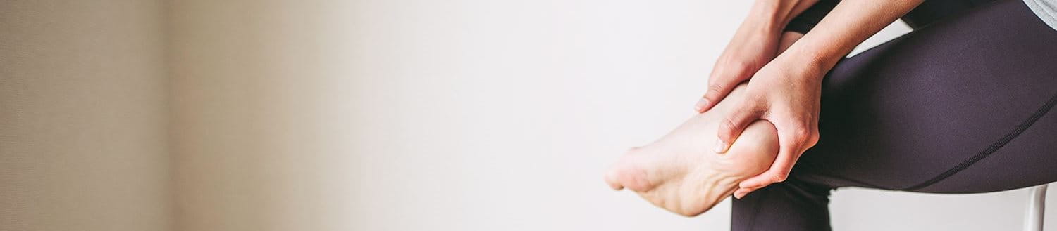 Ein Mann, der schmerzerfüllt seinen Fuß mit Fersensporn betrachtet.