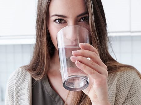 Frau trinkt aus Wasserglas