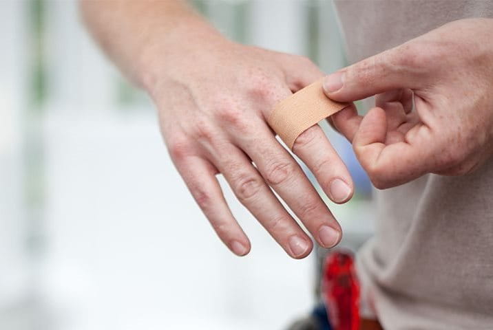 Handwerker klebt Pflaster auf seinen Finger