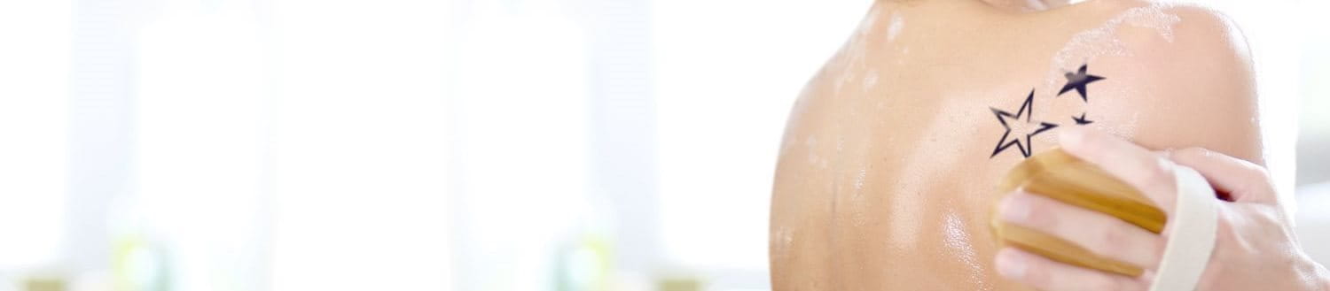 Frau mit Tattoo auf der Schulter duscht