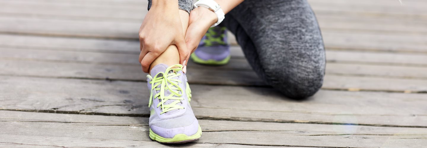 Junge Frau hält sich das schmerzende Fußgelenk