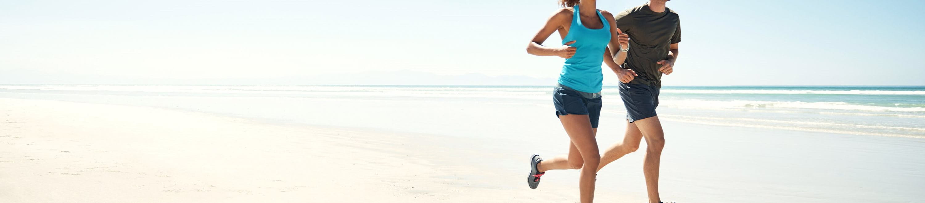 Eine Frau und ein Mann joggen am Strand entlang