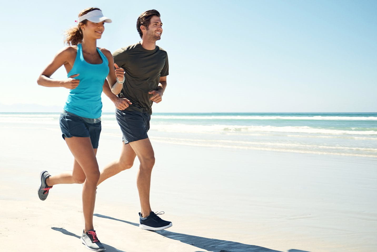 Eine Frau und ein Mann joggen am Strand entlang