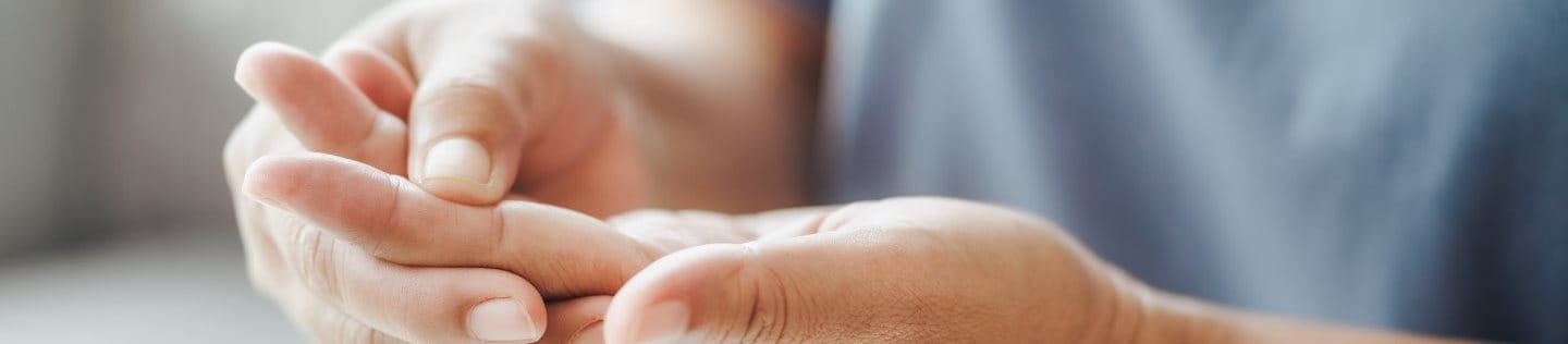 Person mit Karpaltunnelsyndrom hält kribbelnde Hand