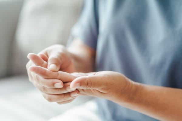 Person mit Karpaltunnelsyndrom hält kribbelnde Hand