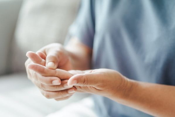 Person mit Karpaltunnelsyndrom hält kribbelnde Hand