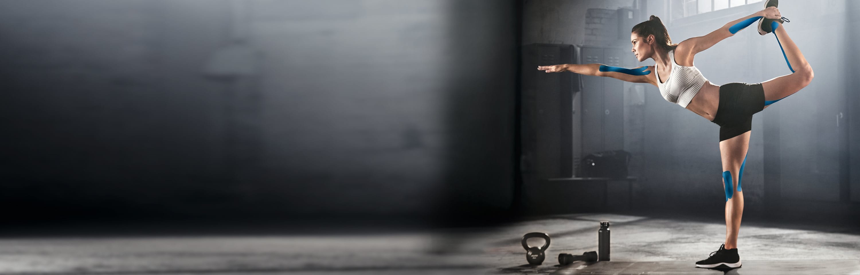 Frau im Fitnessraum mach Übung mit Kniesiologie Tapes an Armen und Beinen