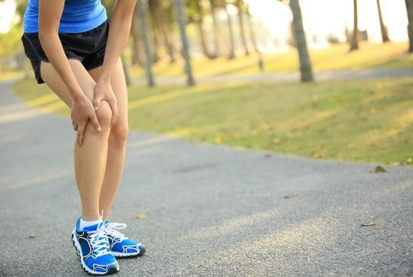 Läuferin hält sich das Knie wegen Knieschmerzen beim joggen