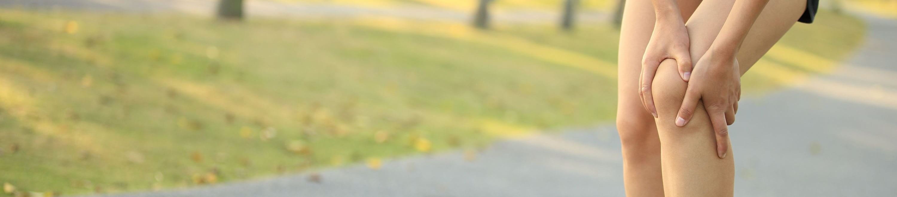 Läuferin hält sich das Knie wegen Knieschmerzen beim joggen