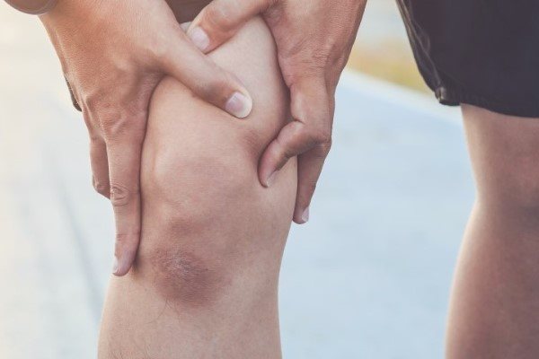 Mann hält sich das Knie  Titel: Sport bei Kniearthrose oder Knieverletzung