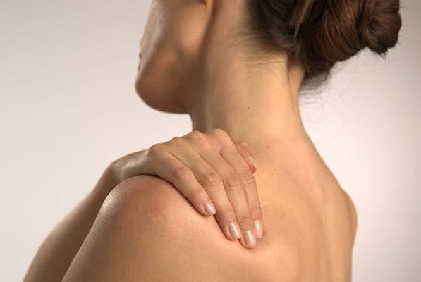 Frau hält sich die Schulter vor Schmerzen