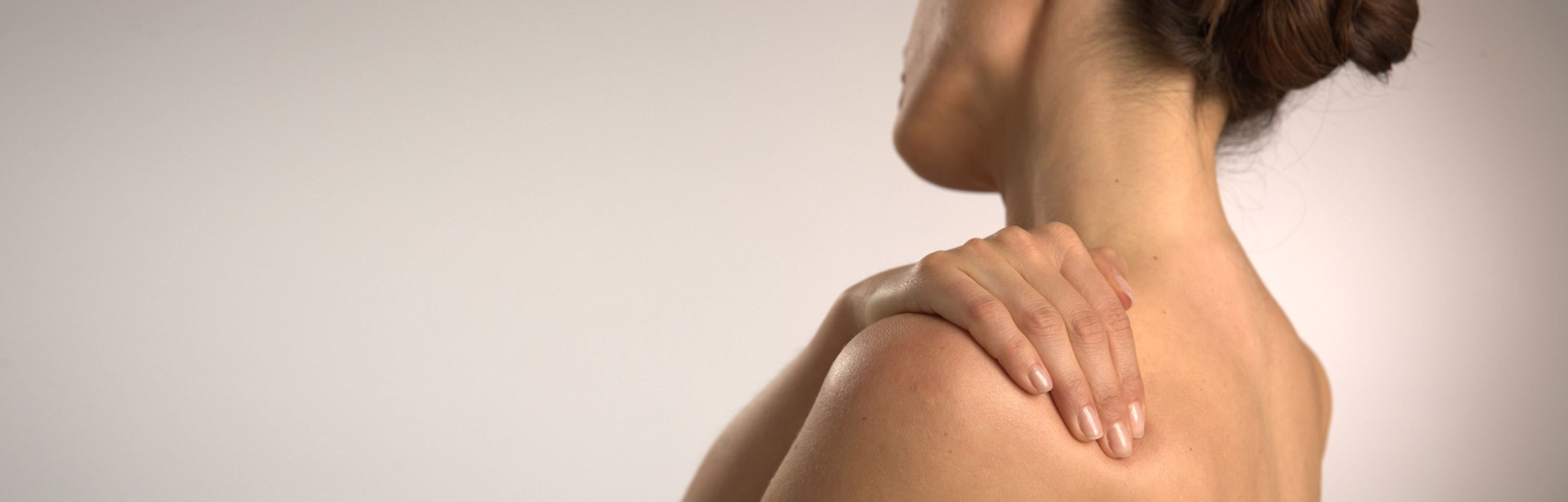 Frau hält sich die Schulter vor Schmerzen