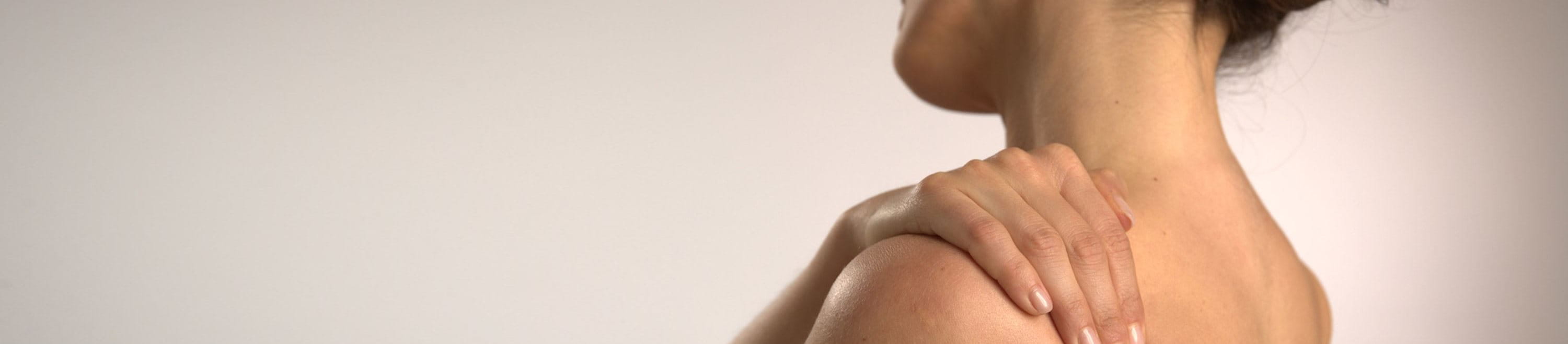 Frau hält sich die Schulter vor Schmerzen