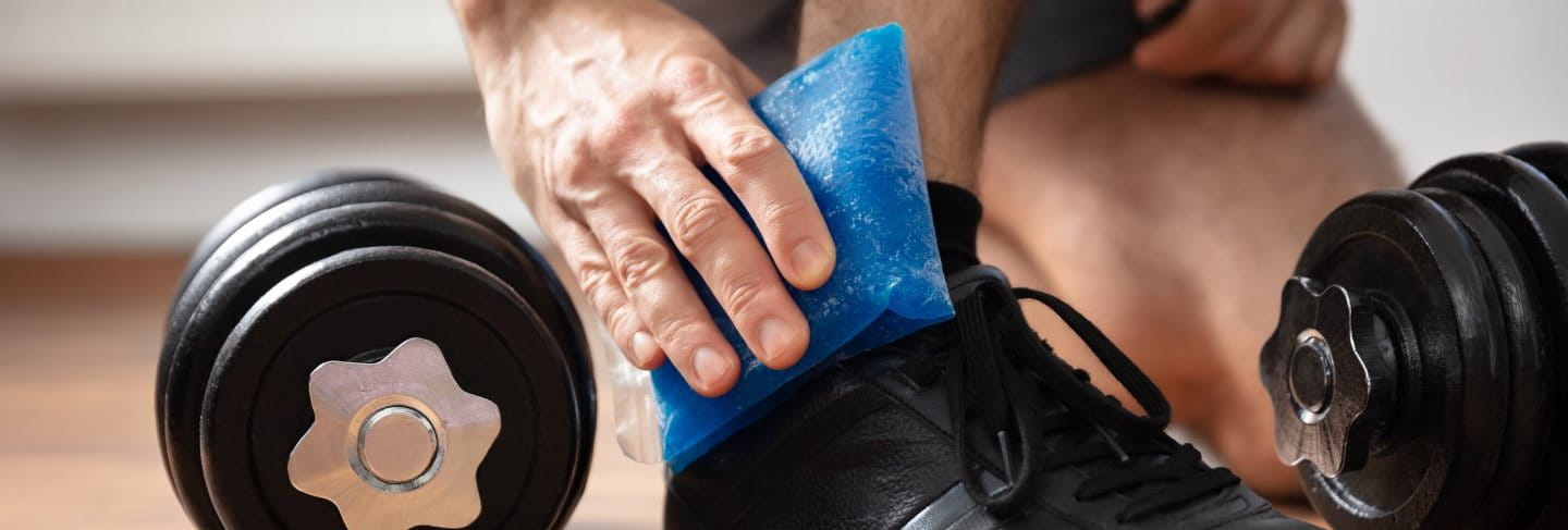 Mann kühlt Sportverletzung im Knie mit einem Kühlpack