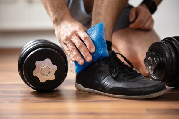 Verletzter Knöchel eines Mannes wird mit Kühlpad gekühlt