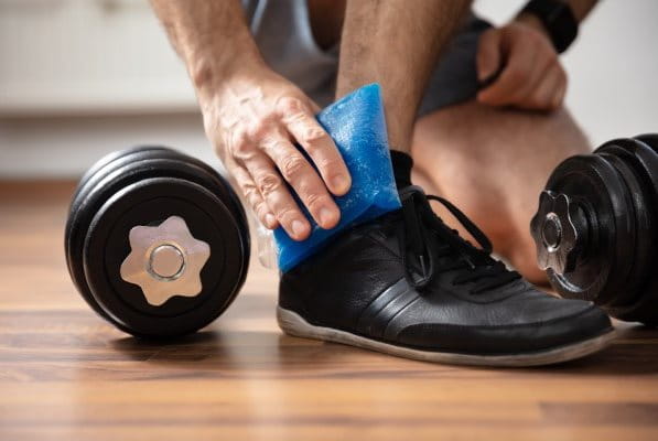 Verletzter Knöchel eines Mannes wird mit Kühlpad gekühlt