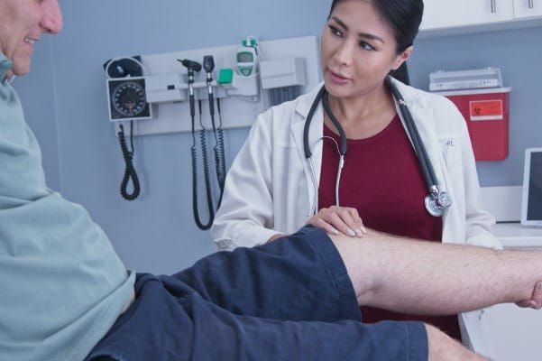 Eine Ärztin untersucht das Knie eines Patienten