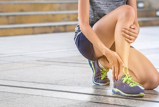 Junge Frau tastet Knöchel ab