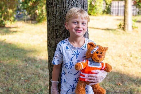 Grundschulkind hält Teddy mit Hansaplast Kinderpflaster im Arm  Titel: Grundschulkind lernt Erste Hilfe mit JRK und Hansaplast