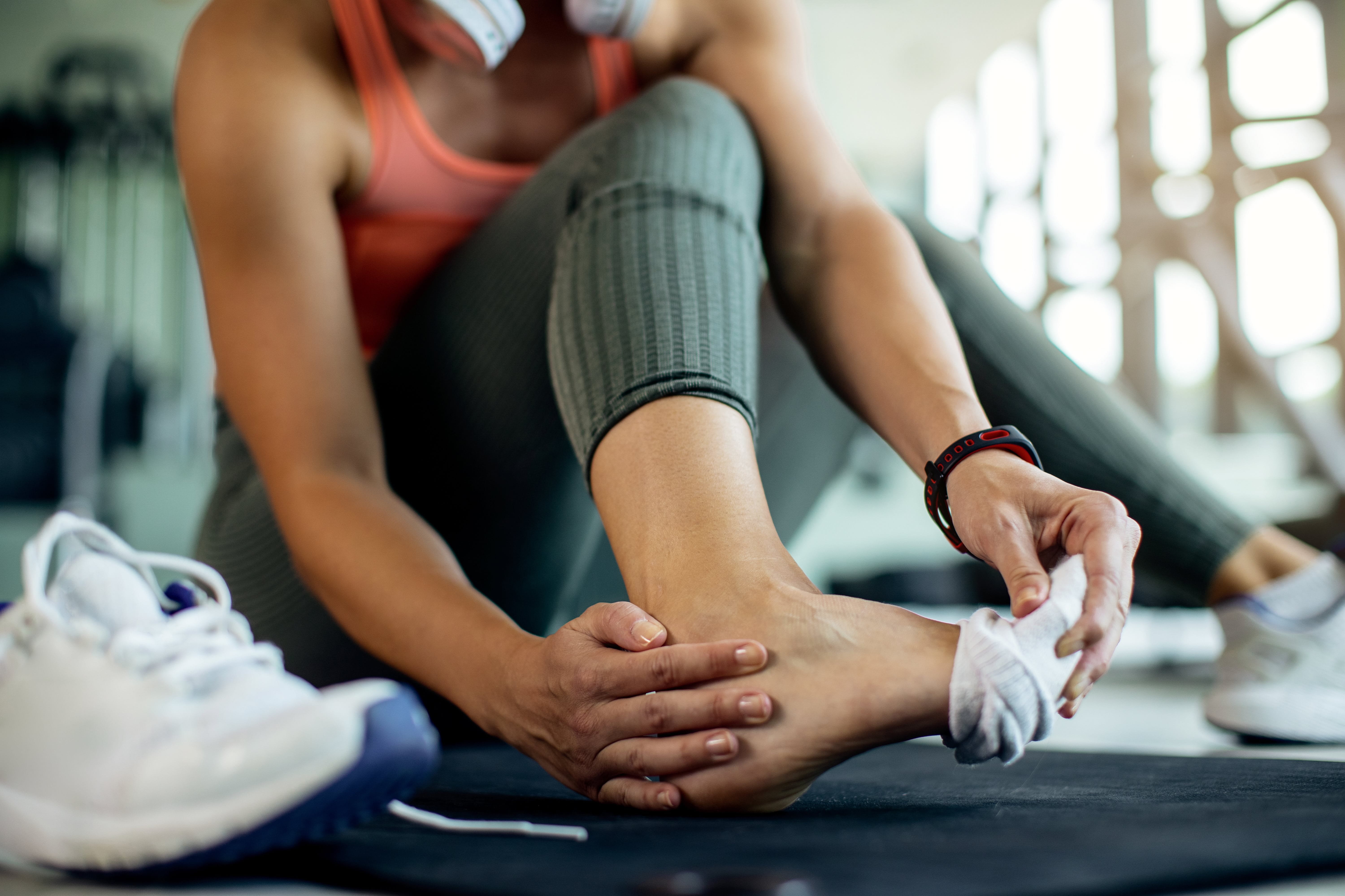 Woman holding her injured ankle in a gym
