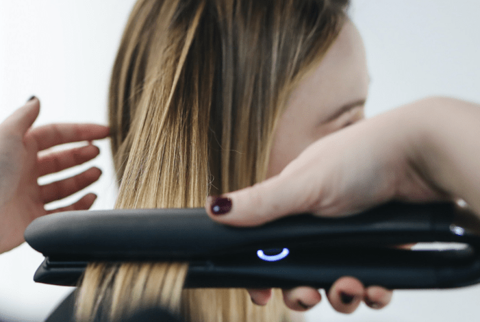 Lady using a hair straightener.