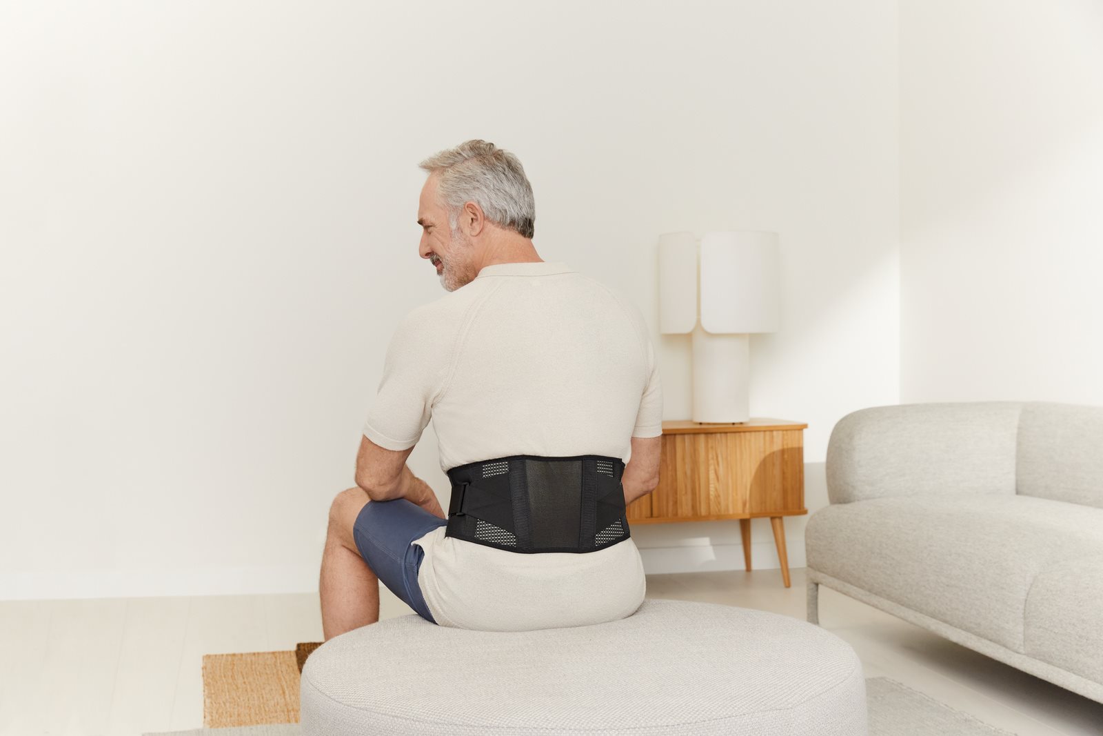 Man wearing a back support at home
