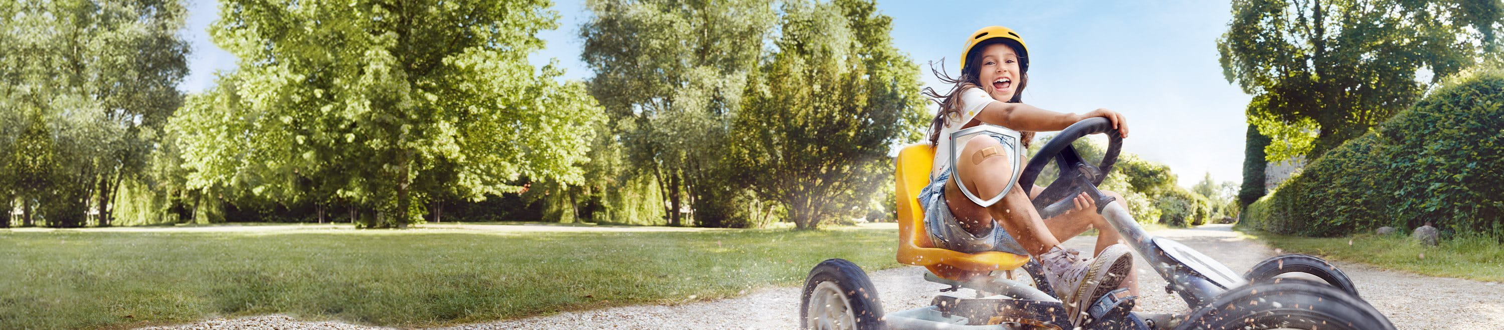 Kind fährt mit einem Pflaster auf dem Knie Go-Kart