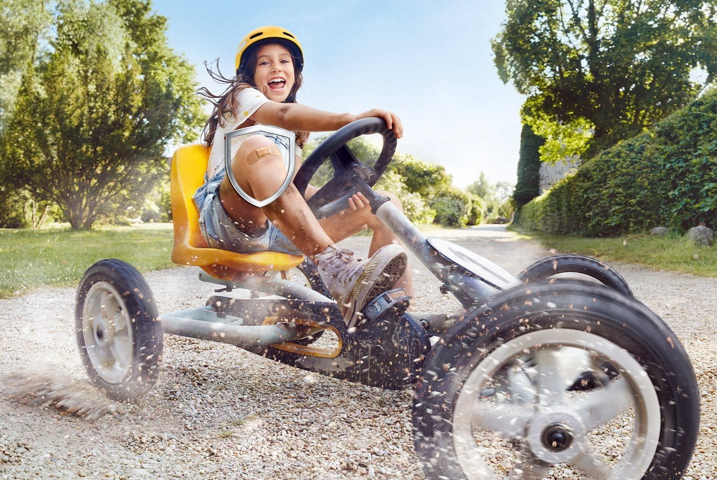 Kind fährt mit einem Pflaster auf dem Knie Go-Kart