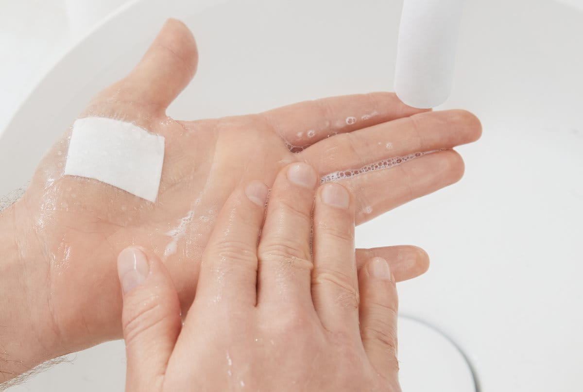 Hand mit Pflaster unter fließendem Wasser