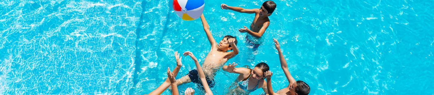 Kinder spielen im Schwimmbad mit einem bunten Ball