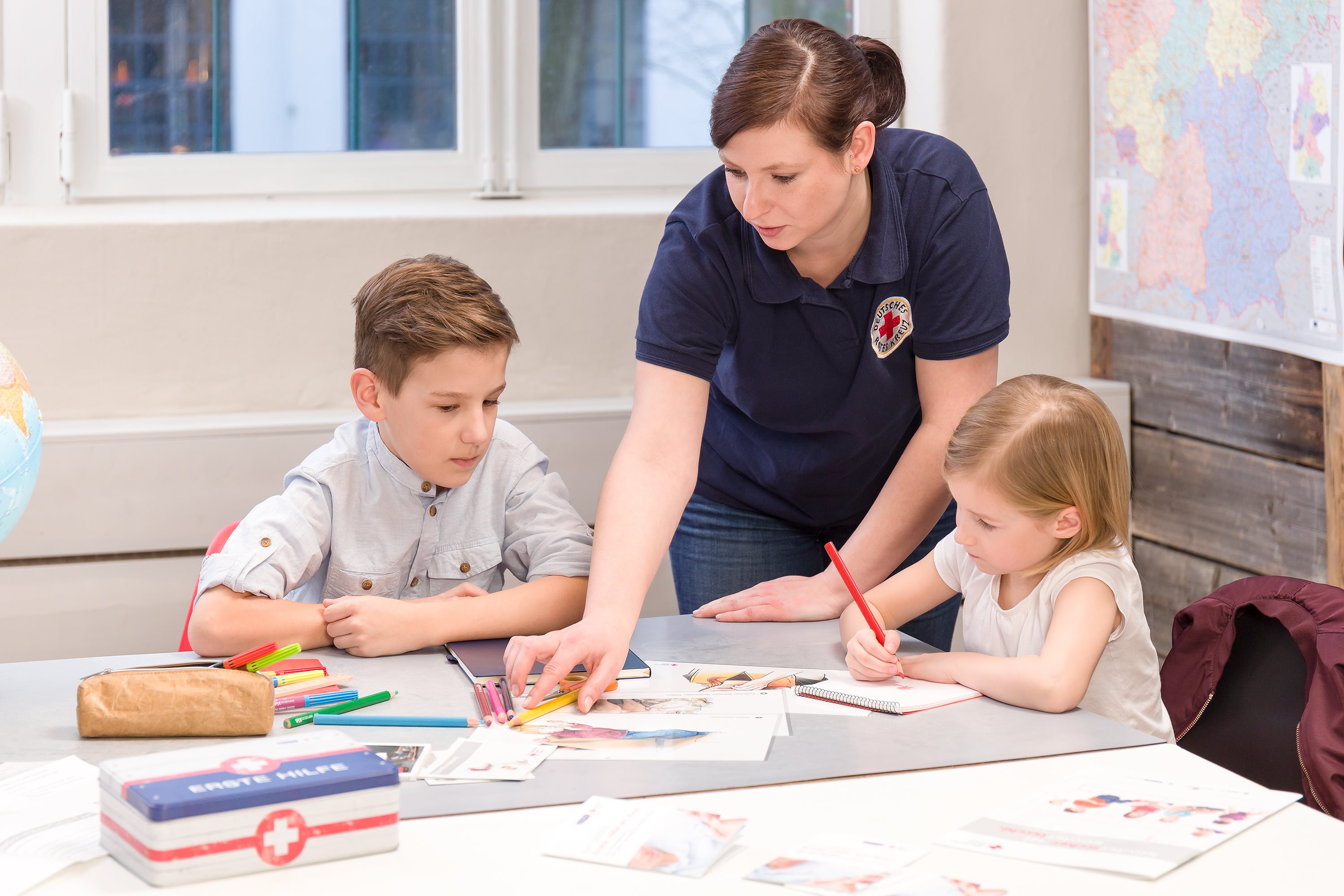 een vrouw die voor het Rode Kruis werkt, leert kinderen over eerste hulp