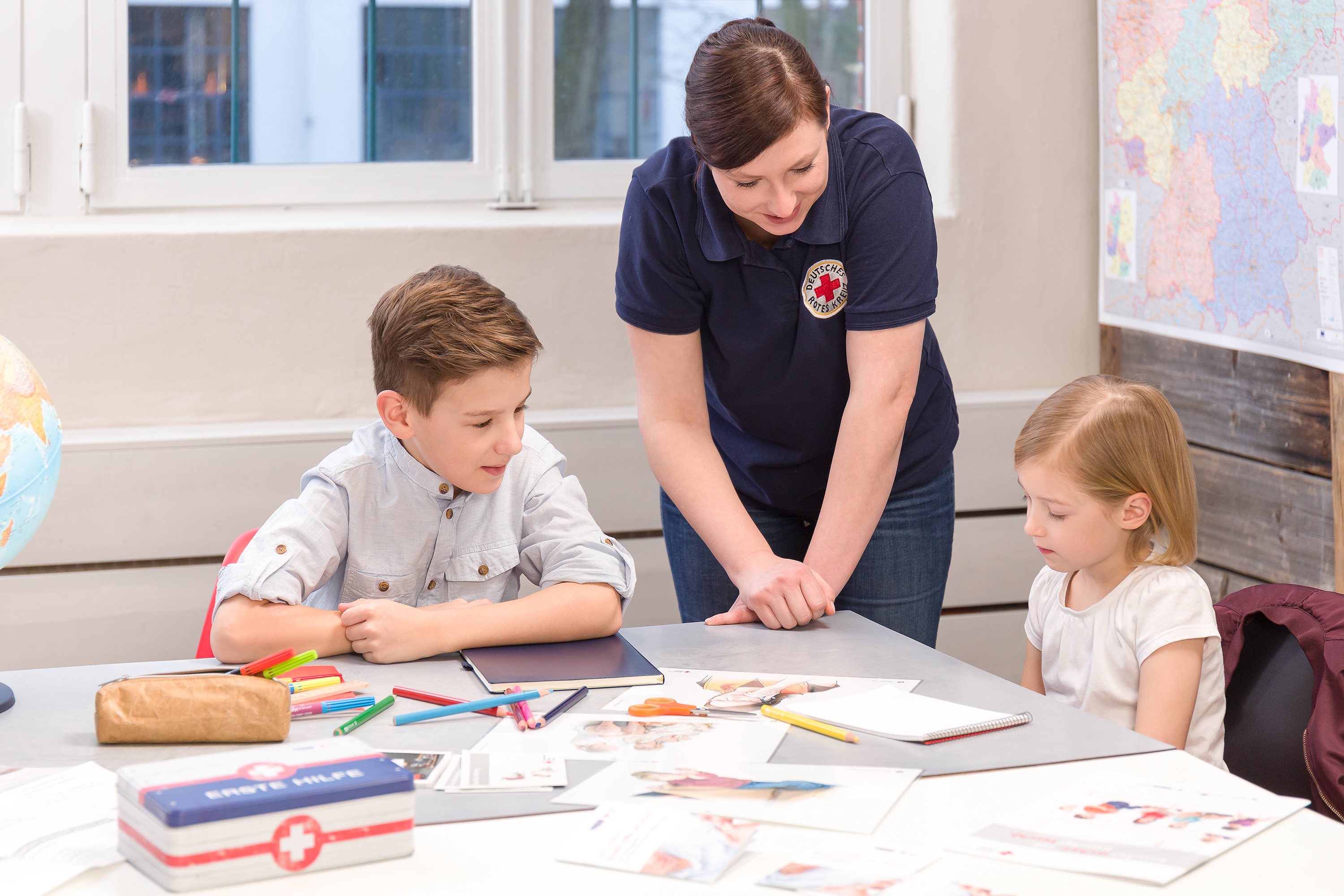 een vrouw die voor het Rode Kruis werkt, leert kinderen over eerste hulp
