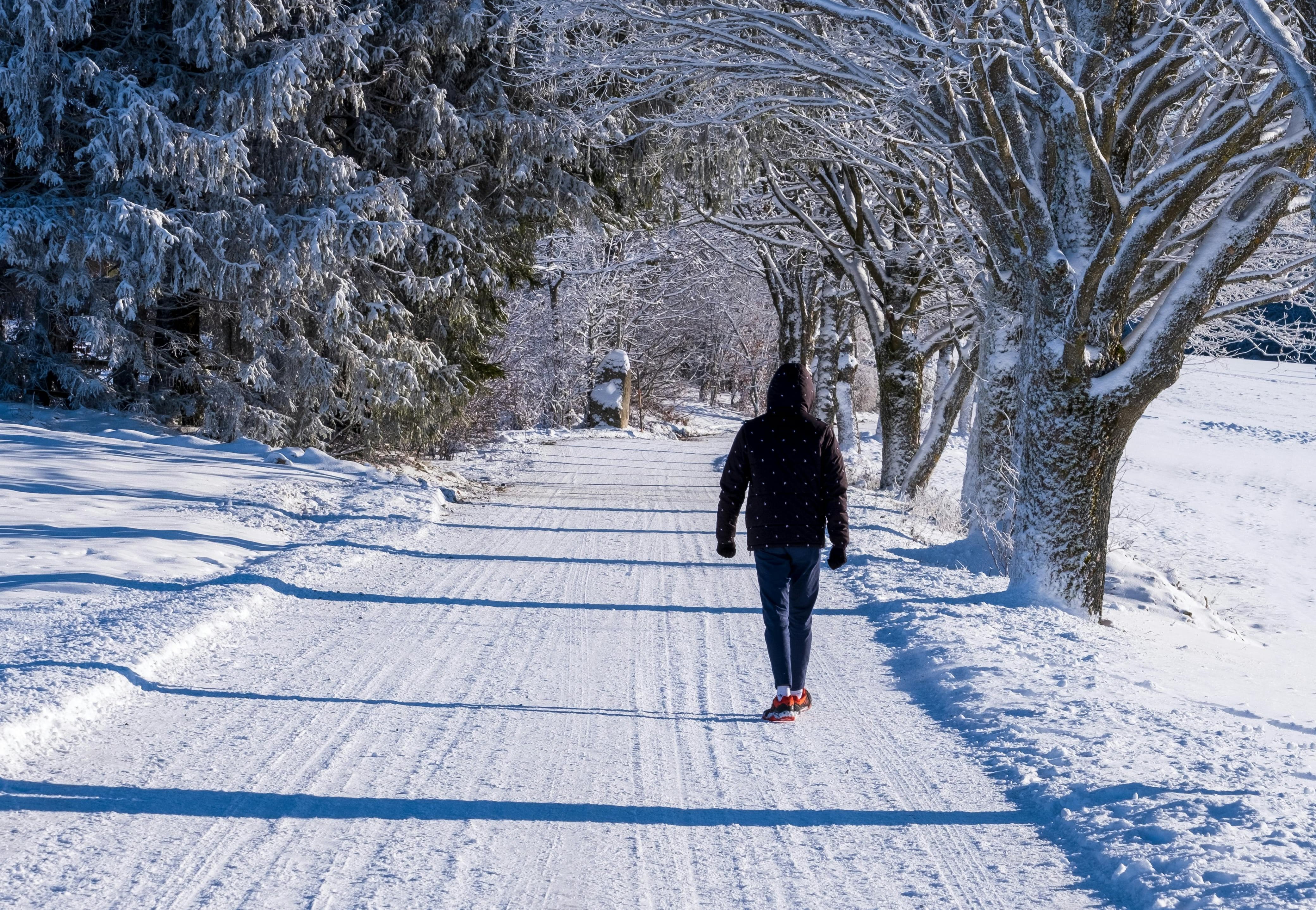 EIn Mann der in einer verschneiten Winterlandschaft spazieren geht.